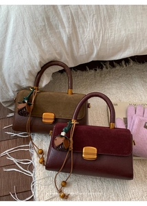 Detail of suede and leather crossbody bag featuring gold hardware and fringe charm