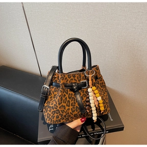 Detail of leopard print bucket bag with black handles and beaded tassel charm