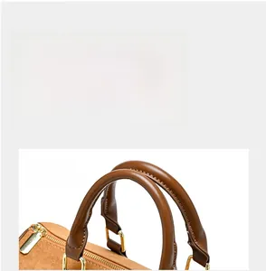 Detail of reinforced brown handles with gold-toned metal buckles on a Boston bag