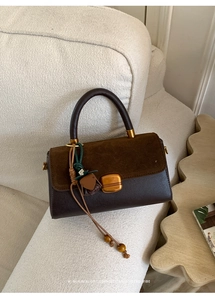 Close-up of retro dark brown leather handbag with suede flap and gold twist lock detail