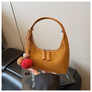 Détail d'un sac demi-lune en daim jaune gingembre avec pompons en fourrure et perles en bois