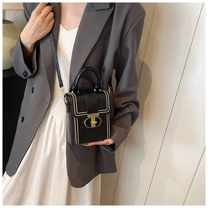 Detail view of black leather crossbody bag with white bead trim and gold buckle on a model