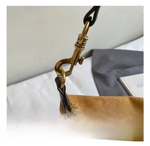 Close-up of premium brass-tone lobster clasp and brown suede texture on shoulder bag