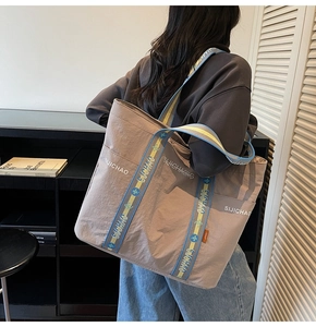 Detailansicht der taupefarbenen Nylontasche mit gewebtem Gurt und Marken-Schriftzug
