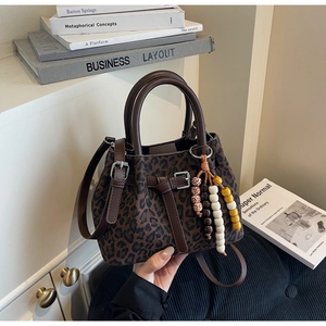 Detail of leopard print crossbody bag with wooden beads and leather handles on books