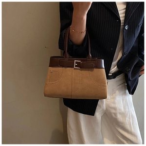Detail of two-tone crossbody handbag featuring contrast stitching and metallic buckle accents
