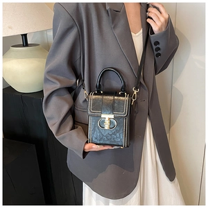 Close-up of black crossbody bag featuring gold hardware and rivet details on the flap