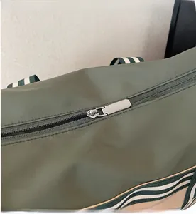 Détail de la fermeture éclair en métal argenté sur le sac de voyage en nylon vert armée