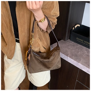 Detail of dark brown suede crescent bag featuring retro wooden beads and cross charm decoration
