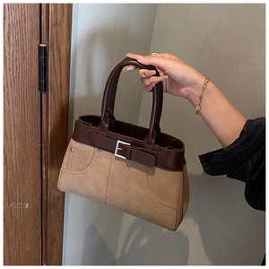 Detail of retro color-block handbag showing khaki suede fabric and buckle strap