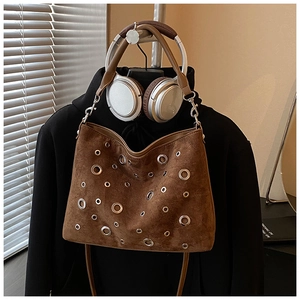 Détail du sac bandoulière en daim marron avec œillets métalliques de style bohème