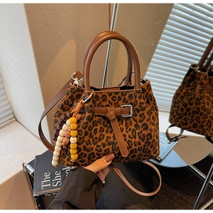 Detail view of leopard print bucket bag with leather handles and decorative wood beads