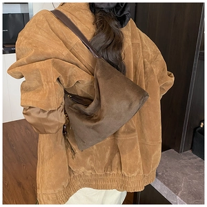 Detail of dark brown suede hobo bag with leather strap worn by a model in winter style