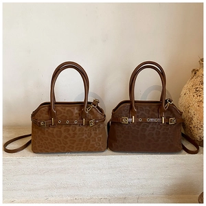 Detail of leopard print tote bags with vintage metal buckles on elegant stone steps