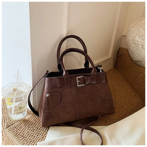 Detail of dark brown handbag showing suede and smooth leather texture with buckle strap