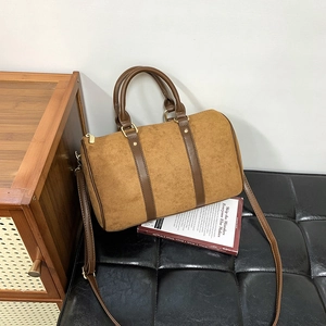 Detail of a brown suede Boston handbag with leather straps and gold metal zippers