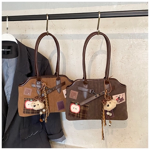 Detail of suede tote bag with apple embroidery and cute plush bear charm accessories