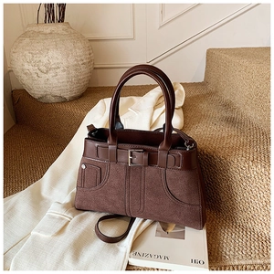 Detail of dark brown handbag showing mixed suede texture and retro buckle accent