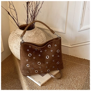Vue détaillée du sac en daim marron avec des œillets argentés et rivets décoratifs