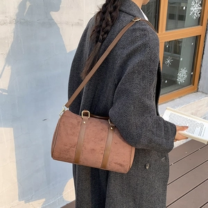 Close-up of brown suede Boston bag with golden hardware on grey wool coat