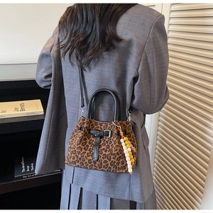 Leopard print bucket bag detail with black leather handles and beaded charm accessory