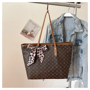 Détail du sac cabas marron foncé avec motif monogramme géométrique et ruban imprimé léopard