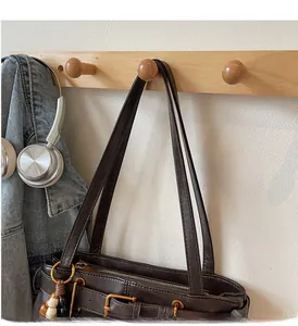 Close-up of deep brown leather tote bag with metal buckles and zipper detail