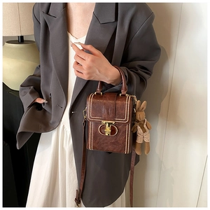 Vertical brown leather handbag with gold buckle and cute rabbit pendant detail