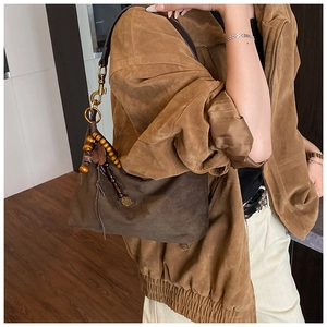 Detail of vintage suede shoulder bag featuring wooden beads and leather fringe charm