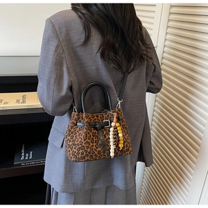 Detail of leopard print bucket bag with leather handles and decorative beaded charm