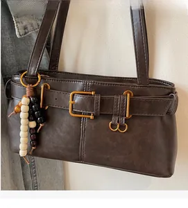 Detailed shot of brown vintage handbag with belt buckle and multi-color beaded pendant