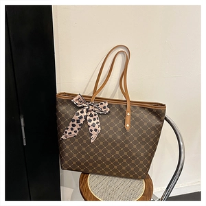 Sac cabas marron à motifs losanges avec foulard en soie léopard sur un tabouret en bois