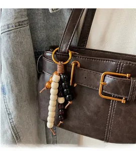 Detail of retro wooden bead bag charm with gold metal ring hook on a brown leather bag