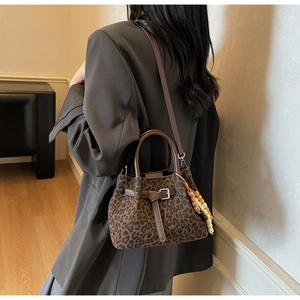 Detail of leopard print bucket bag featuring brown leather straps and wooden bead charm