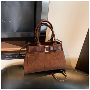 Brown frosted suede and smooth leather handbag displayed with vintage art props and books