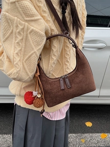 Sac hobo en daim marron foncé avec breloques décoratives dans un décor de style automne