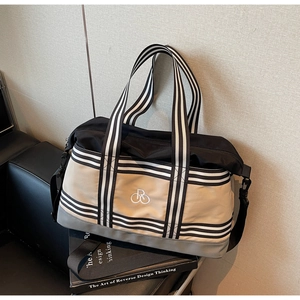 Détail du sac de voyage montrant les anses rayées et le logo brodé sur toile kaki