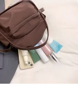 Detail view of large capacity dark brown nylon bag showing storage for phone and cosmetics
