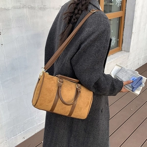 Brown faux suede Boston bag with gold hardware worn with a dark grey winter coat