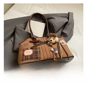 Detail of vintage tote bag with apple embroidery, plaid patches, and plush bear charm