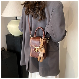 Macro detail of retro brown leather phone bag with gold rivets and cute rabbit pendant