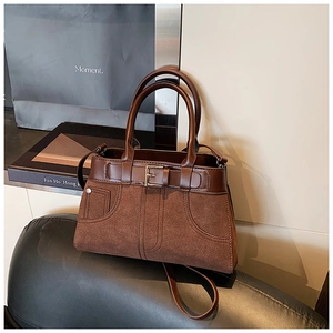 Detail of a brown suede and leather crossbody bag with metallic square buckle and strap