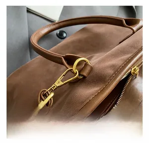 Detail shot of the polished gold-tone metal hook and zipper on a brown leather tote bag
