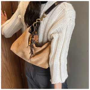 Detail of camel suede hobo bag with ethnic beaded charm and wide brown strap
