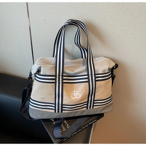 Gros plan d'un sac de voyage en toile avec sangles rayées et logo brodé sur siège en cuir