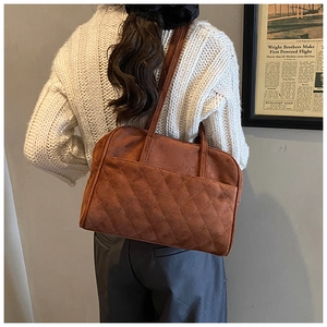Détail du sac cabas en daim marron avec motif matelassé en losanges sur la poche avant