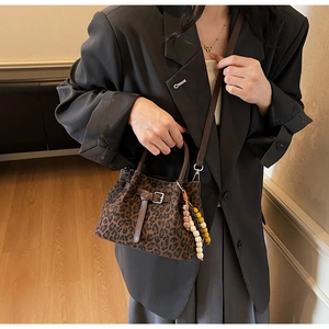 Detail of leopard print crossbody bucket bag with beaded charm and leather strap