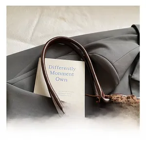 Detail showing comfortable brown leather handles and cute bear plush charm on tote bag