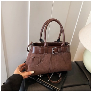 Macro shot of dark brown matte suede handbag with leather trim and metal buckle detail