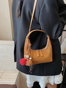 Sac demi-lune en daim jaune avec pompons en peluche porté par un mannequin